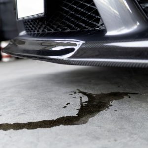 puddle of oil on concrete underneath a car 