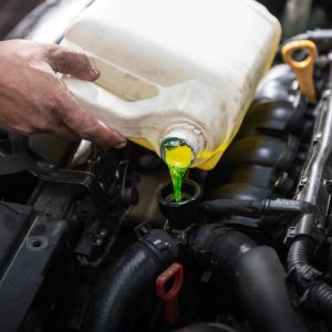 someone pouring coolant from a bottle into a reservoir 